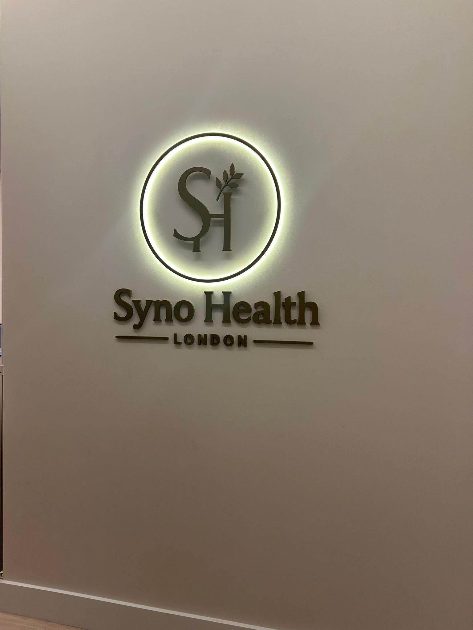 Illuminated Syno Health London logo inside the clinic