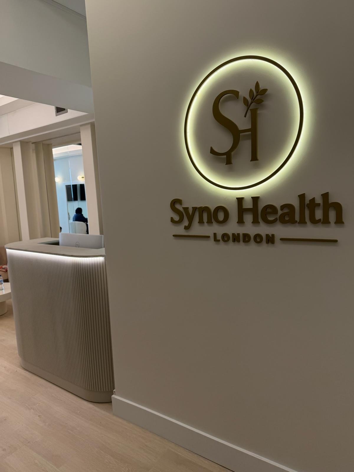 Syno Health clinic reception and illuminated wall logo